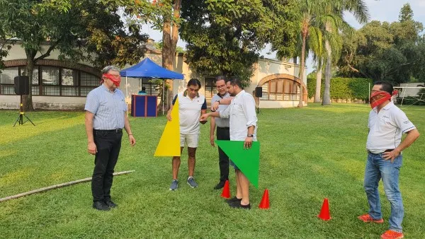 Un grupo de trabajadores realizando una dinámica de integración empresarial de equipos en un parque al aire libre.