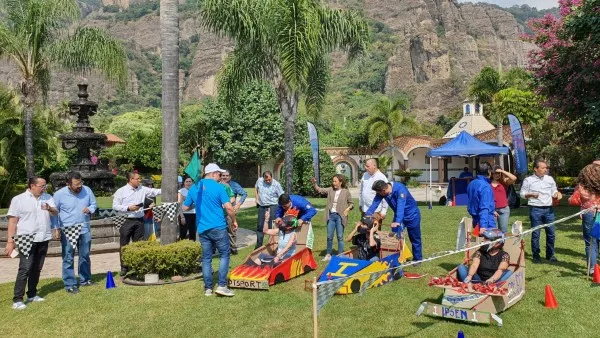 Personas reunidas realizando una dinámica de rally en un espacio abierto y verde cerca de un cerro de integración de equipos