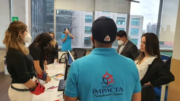 Coach realizando una dinámica con trabajadores en una oficina porque lo contrataron para mejorar la motivación de equipos en una empresa.