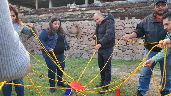 Personas participando en talleres de comunicación realizando una dinámica con cuerdas.