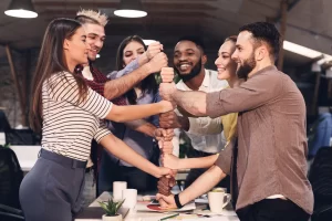 Emprendedores celebrando logros en equipo en la oficina, destacando el impacto del team building en la cohesión y el éxito empresarial.